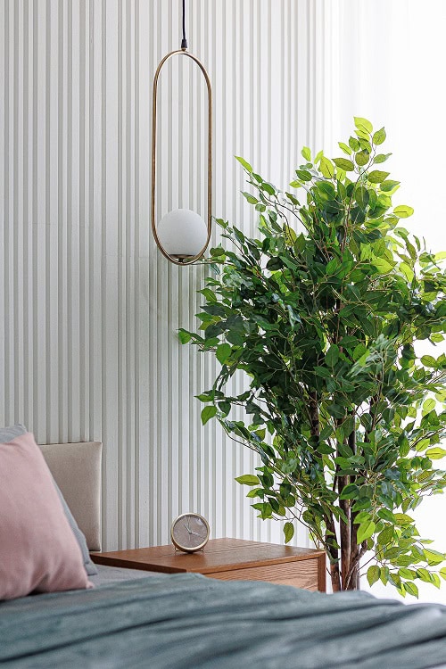 Modern bedroom in an apartment in Becici, Montenegro: designer light fixture, slat wall, and houseplant.