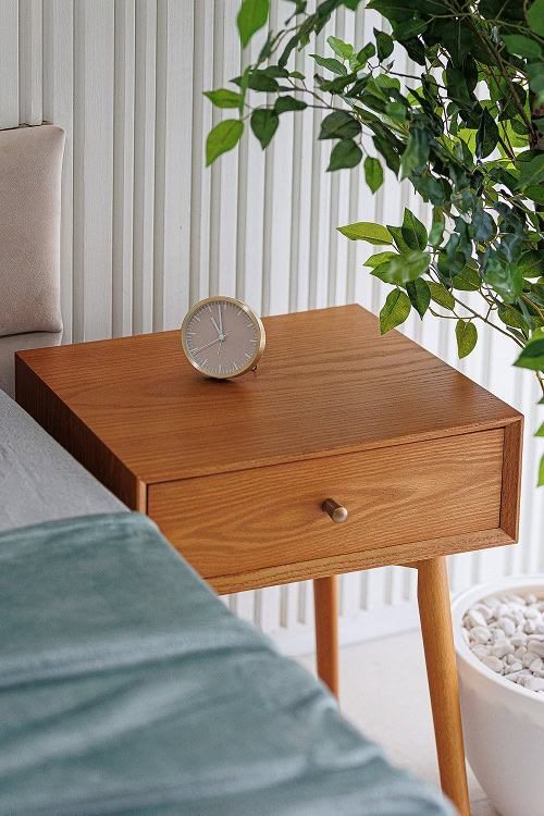 Wooden bedside table in a bedroom interior of an apartment in Bečići, Montenegro, featuring a slatted wall panel.