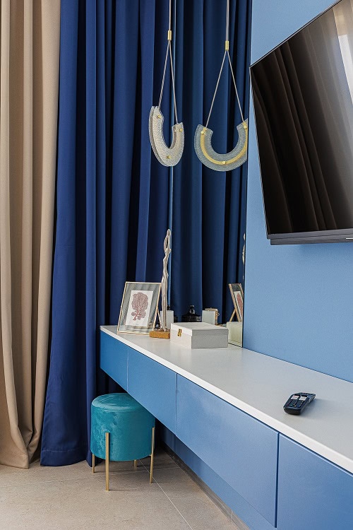Modern living room in a Becici apartment, Montenegro: blue furniture, designer lighting, and TV area.
