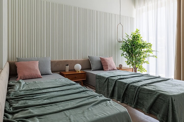 Modern bedroom with two beds in an apartment in Bečići, Montenegro: slatted wall, stylish decor, and panoramic window.