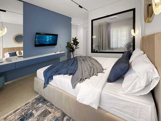 Modern bedroom in an apartment in Bečići, Montenegro: double bed, blue accent wall, and TV area.