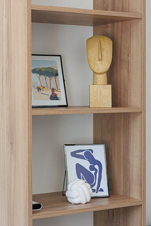 Wooden shelving unit with decor and paintings in a living room interior in Bečići, Montenegro. Stylish living room design.