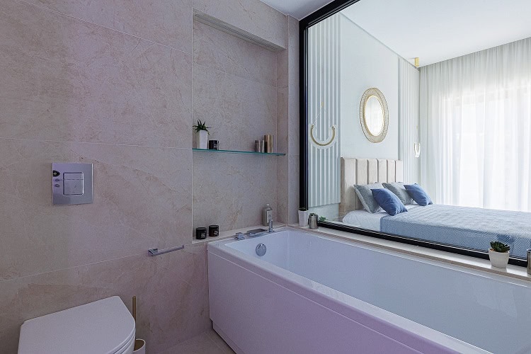 Modern bathroom with a panoramic window overlooking the bedroom in an apartment, Bečići, Montenegro. Marble-effect tile finish.
