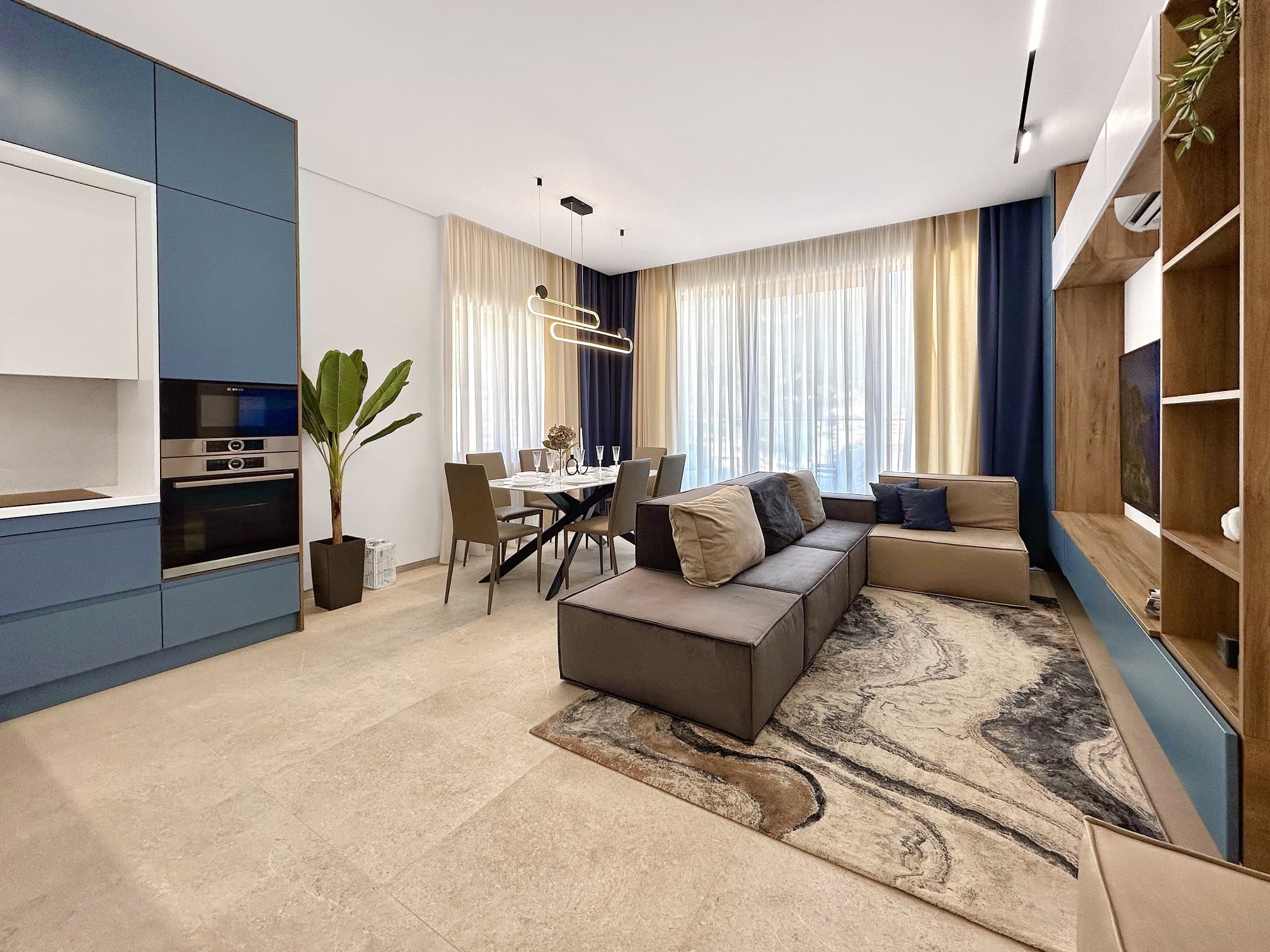Modern living room with kitchen in an apartment, Becici, Montenegro: stylish furniture, dining area, and panoramic windows.