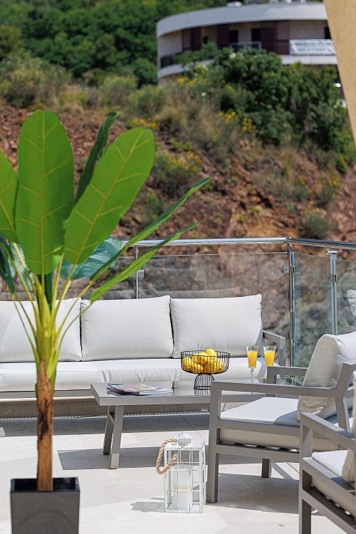 Cozy terrace with patio furniture and mountain views in a Becici apartment, Montenegro. Modern balcony with decor.