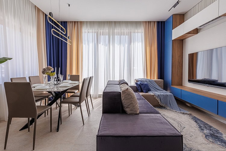 Modern living room with a dining area in an apartment in Bečići, Montenegro: stylish furniture, panoramic windows, and decor.