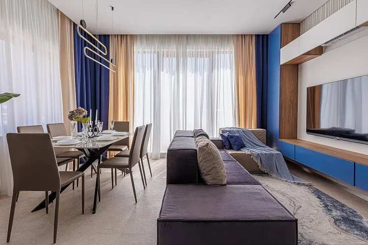 Living room with sofa, dining table, and TV on a blue wall unit.