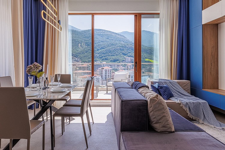 Living room with a panoramic mountain view in an apartment in Bečići, Montenegro: modern furniture and dining area.