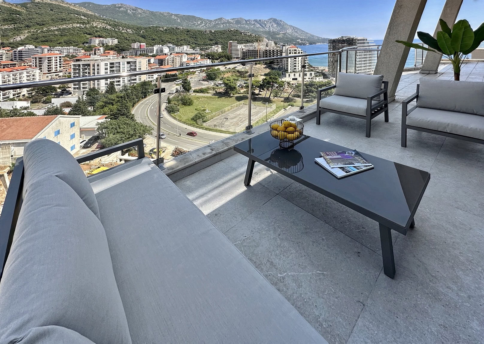 Terrace of an apartment in Bečići, Montenegro: modern furniture, sea, mountain, and city views from a panoramic balcony.