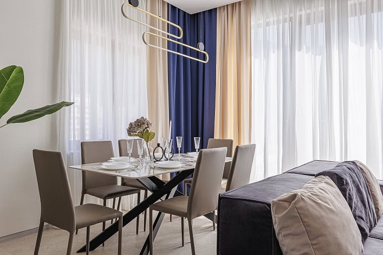 Modern dining area in an apartment in Bečići, Montenegro: stylish table, chairs, and designer chandelier in the living room.
