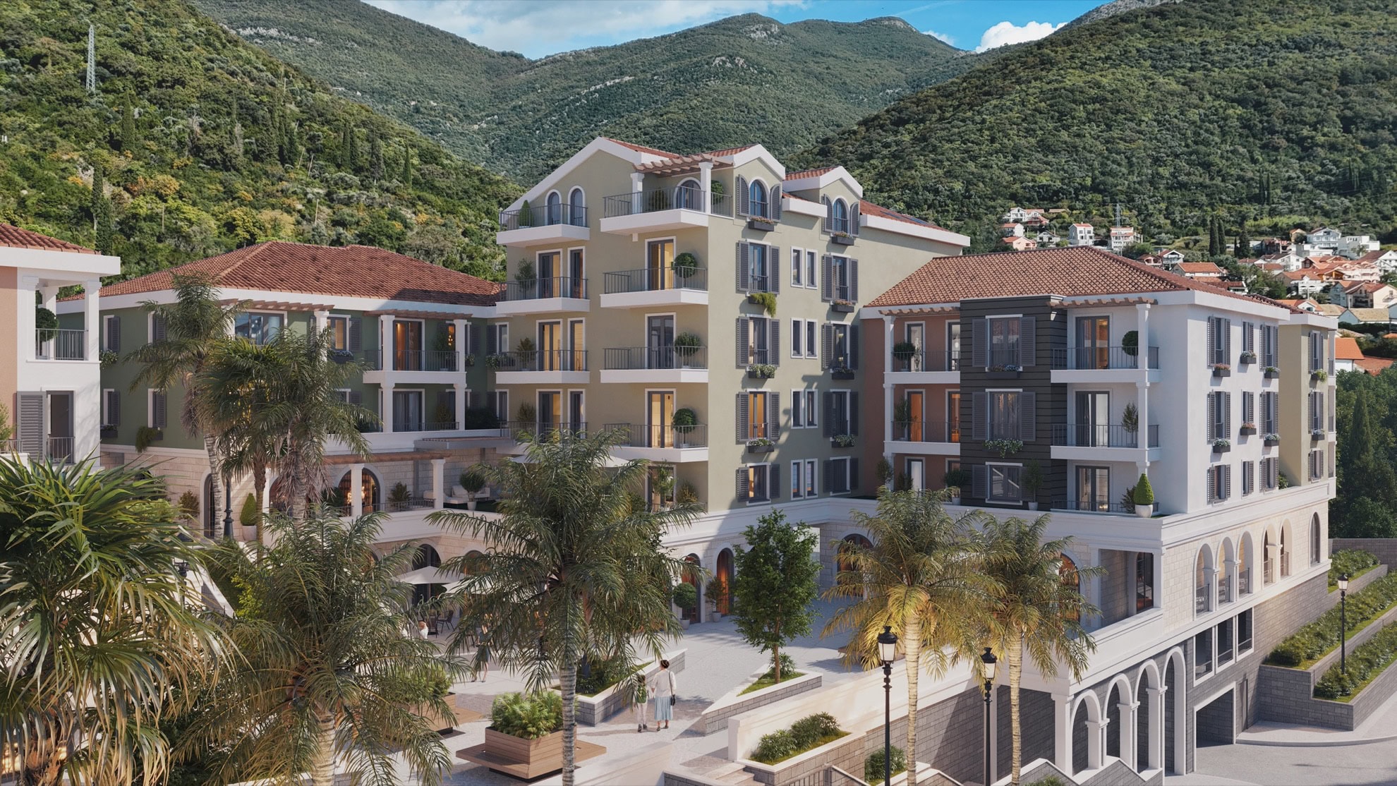 Modern residential complex with terraces and palm trees in Tivat, Montenegro: view of the building facade against the backdrop of mountains.
