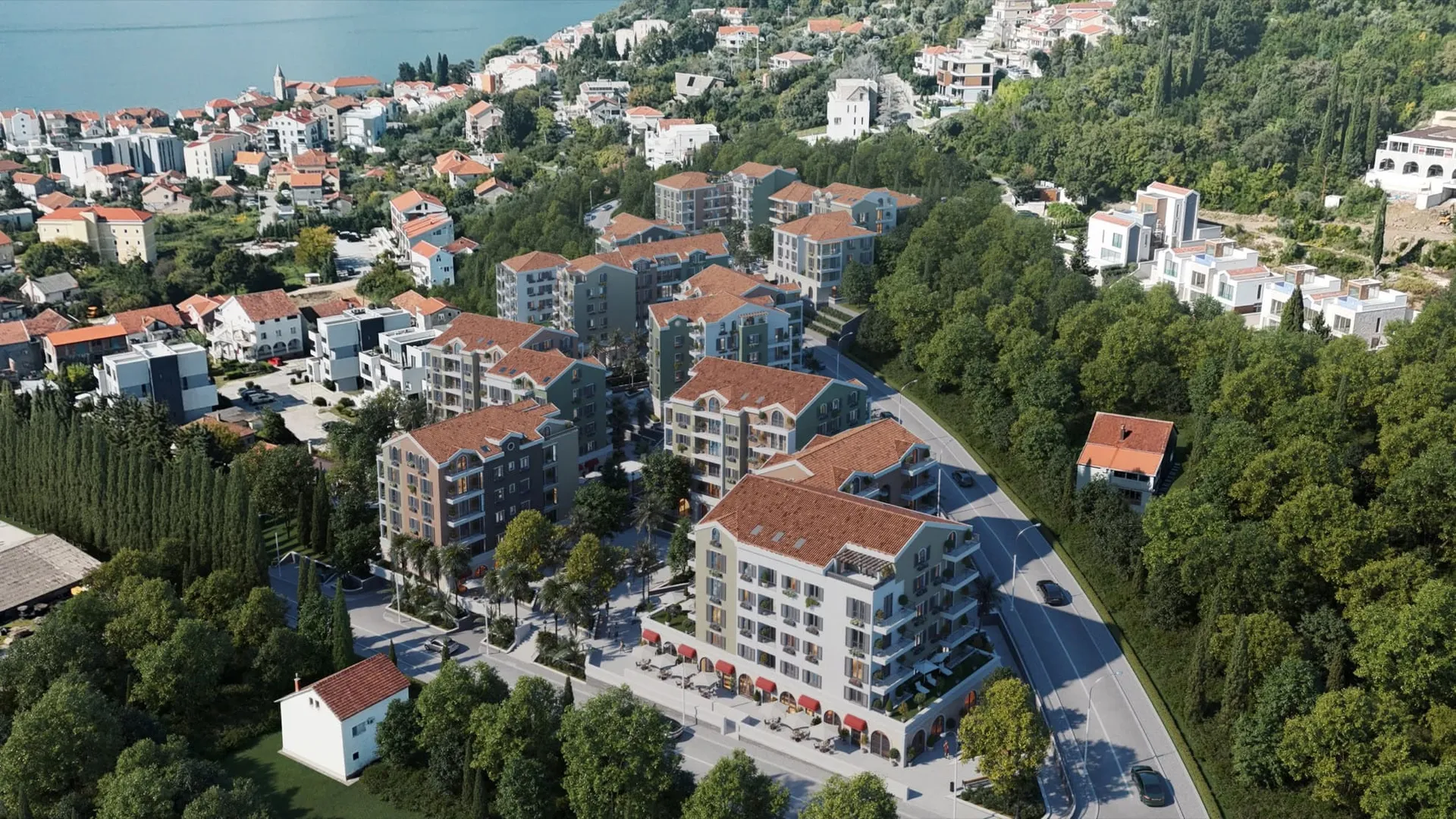 Aerial view of a coastal residential area featuring apartment buildings, roads, and the sea.