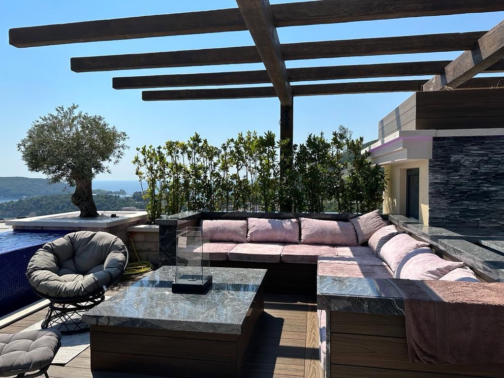 Penthouse terrace in Bečići, Montenegro: a lounge area with a soft sofa, pool, and sea view.
