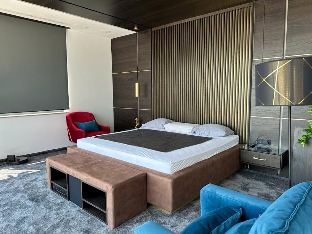 Designer bedroom in a penthouse, Bečići, Montenegro: double bed, slatted wall finish, and upholstered furniture.