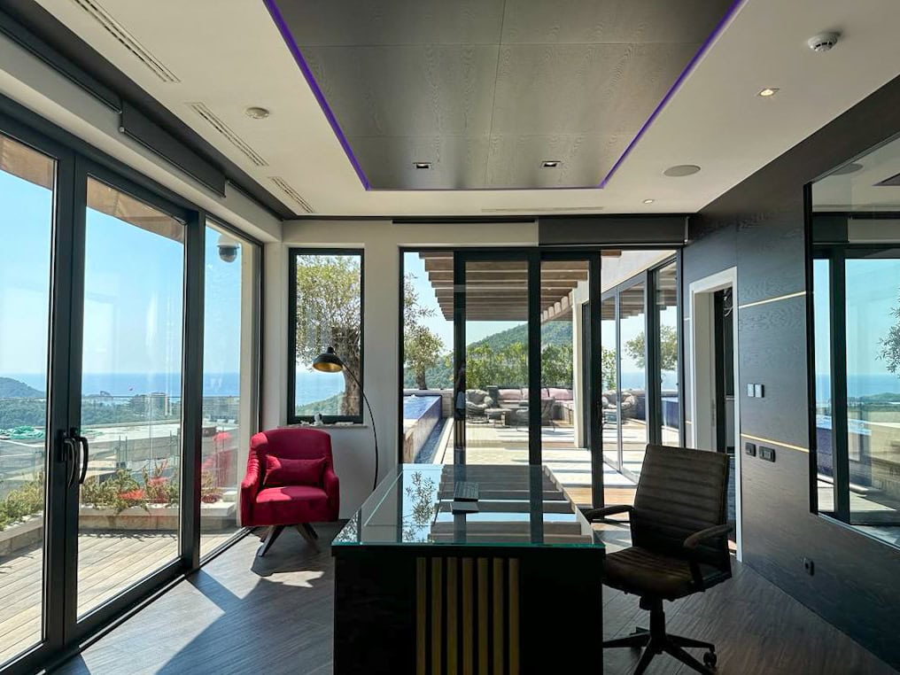 Modern office in a penthouse in Bečići, Montenegro: glass table, panoramic windows with sea and terrace views.