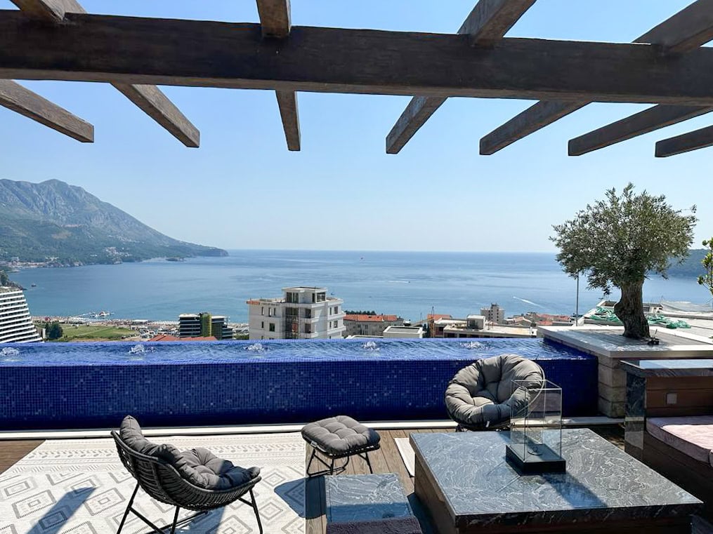 Penthouse terrace in Bečići, Montenegro: infinity pool, lounge area with furniture, and panoramic sea and mountain views.
