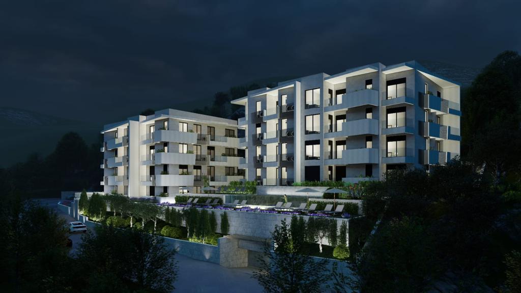 Modern residential complex with a pool in Petrovac, Montenegro: night view of the building with terraces and lighting.