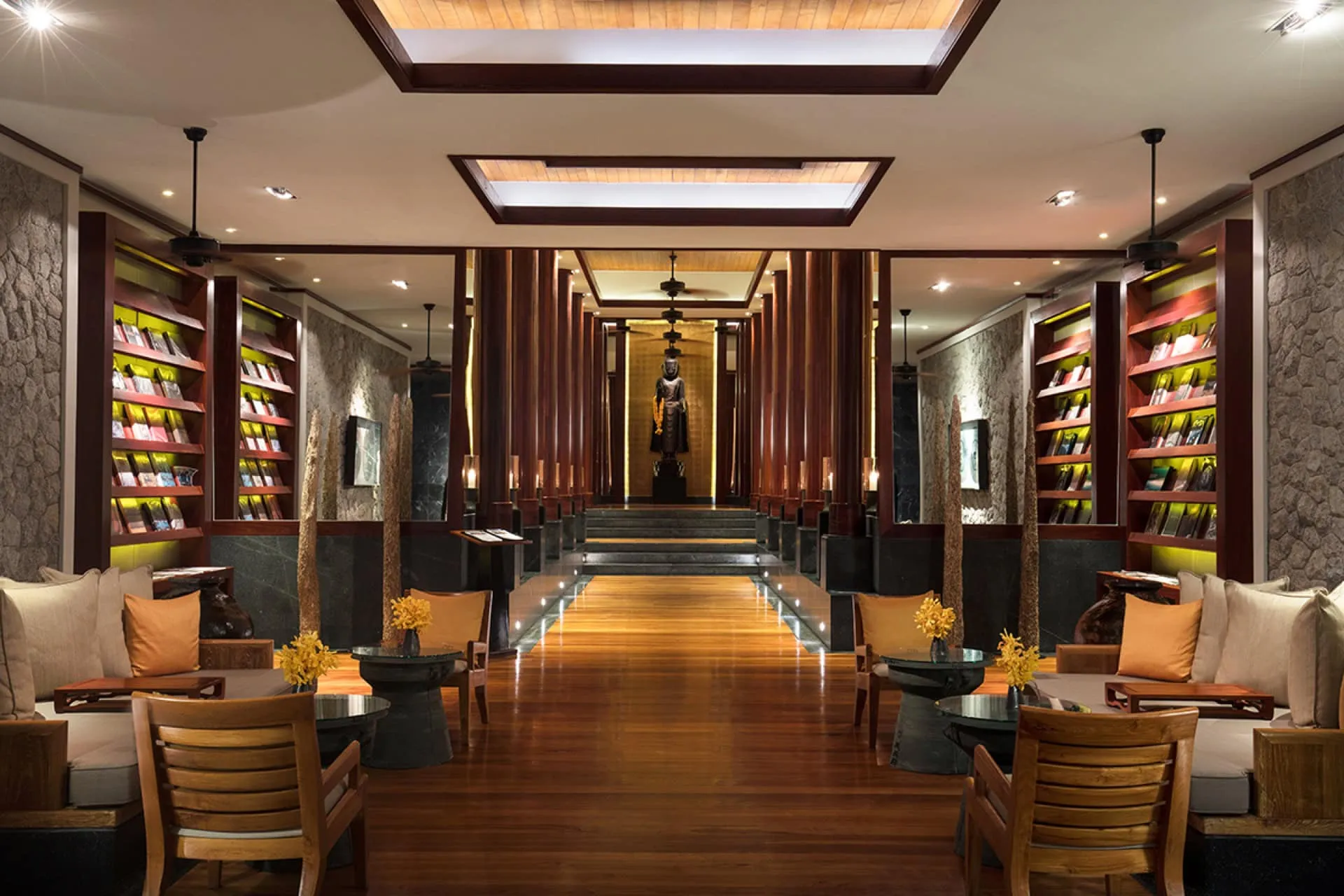 Luxurious interior with wooden floors, brochure shelves, and a Buddha statue at the end of a corridor.