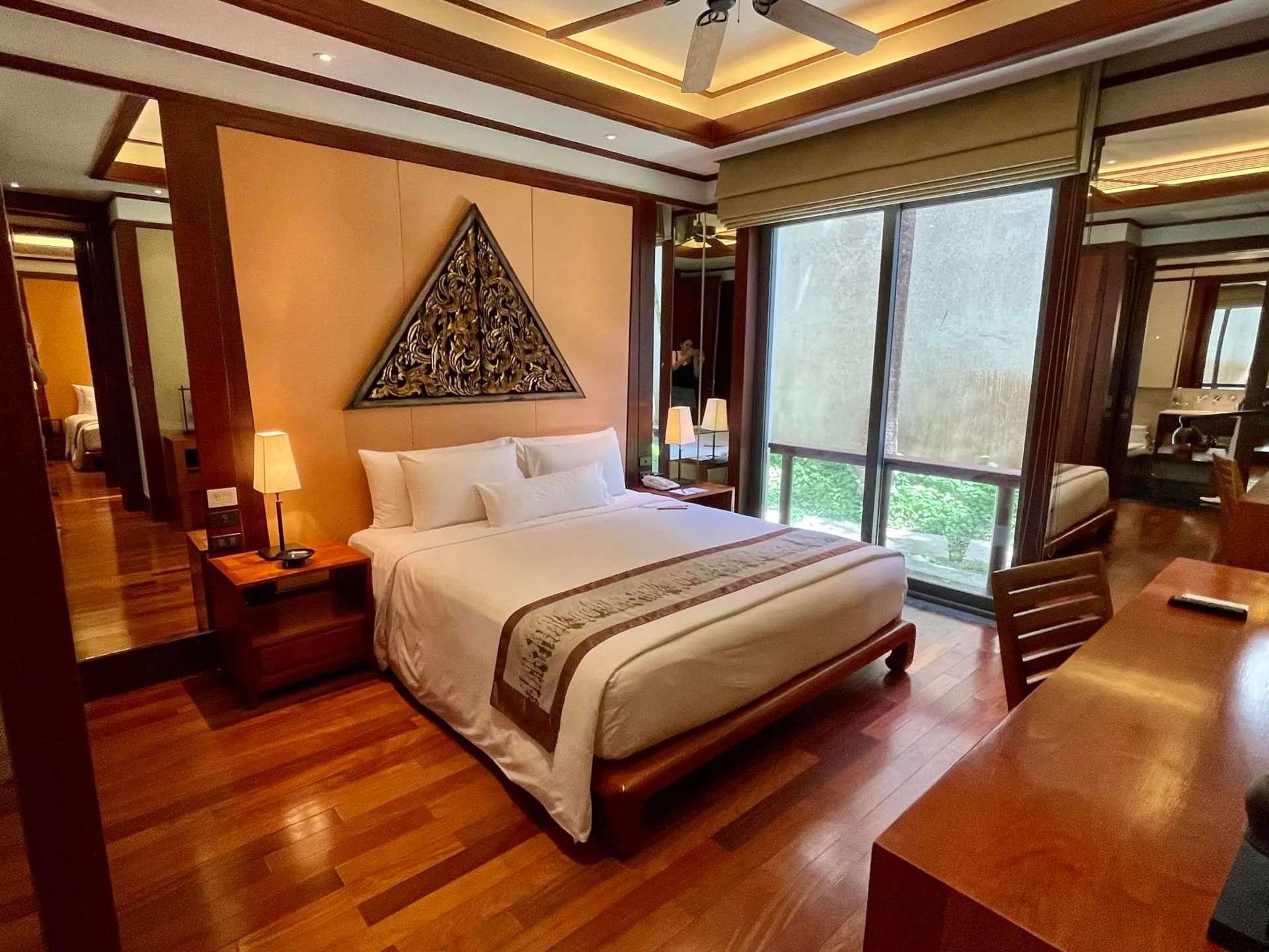 Bedroom featuring hardwood floors, a large bed with white linens, nightstands, and wall art.