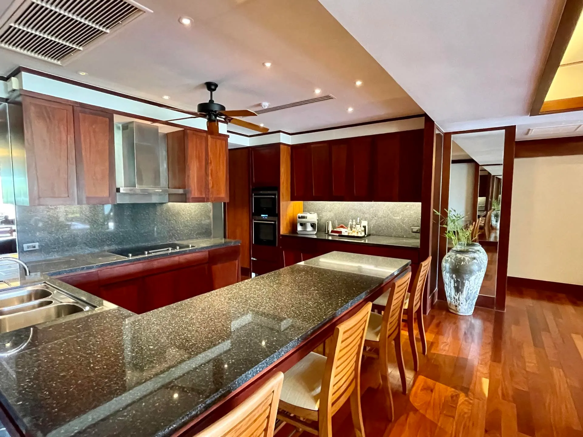 Kitchen featuring dark granite countertops, wooden cabinetry, a central island with chairs, and built-in appliances.