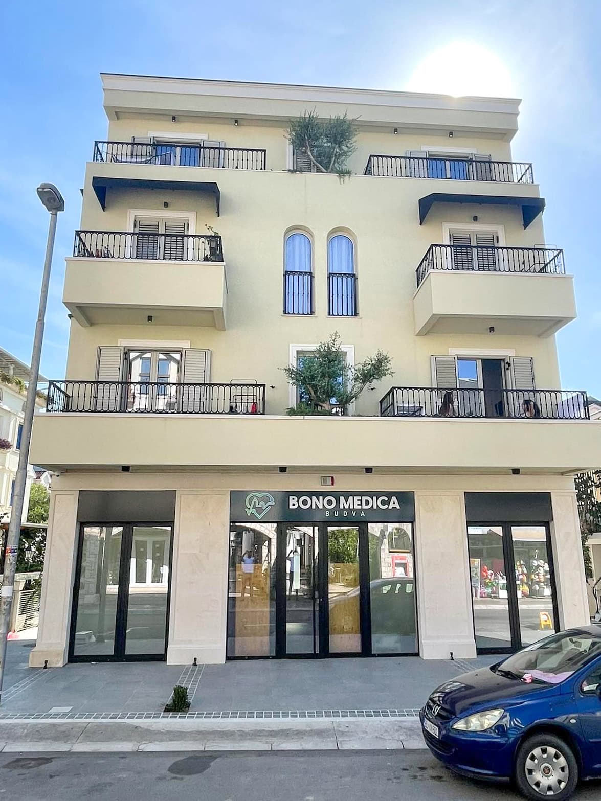 Facade of a modern residential building with the Bono Medica commercial space in Budva, Montenegro, with balconies and terraces.