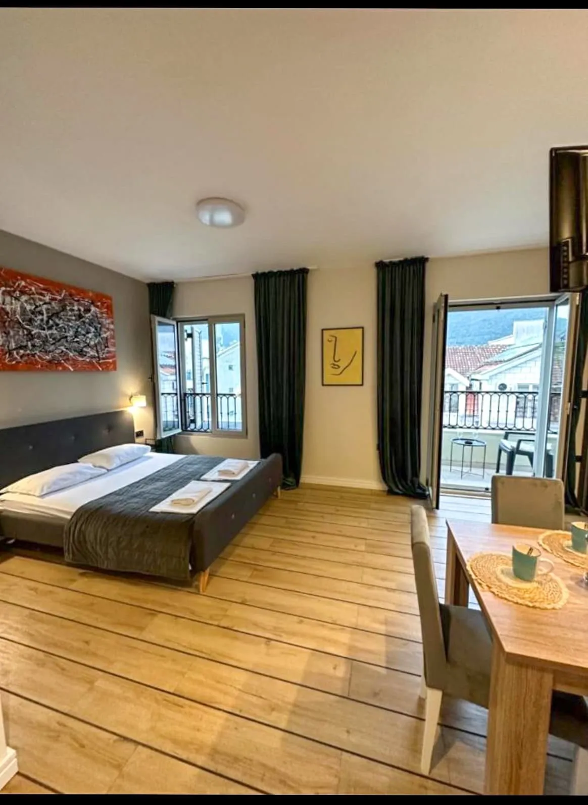 Bedroom with a double bed, wooden flooring, and a dining table near the balcony door.