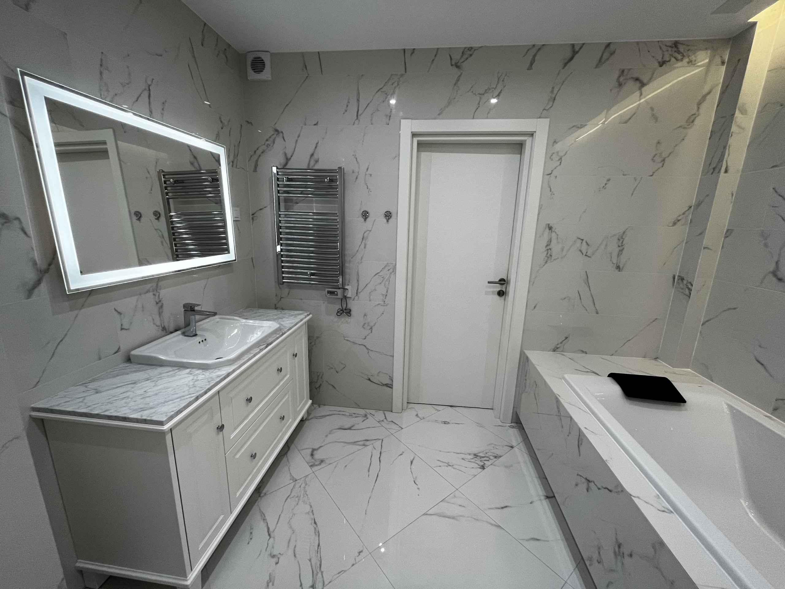 Modern bathroom with marble-style finishes in Kumbor, Montenegro: vanity with sink and illuminated mirror.