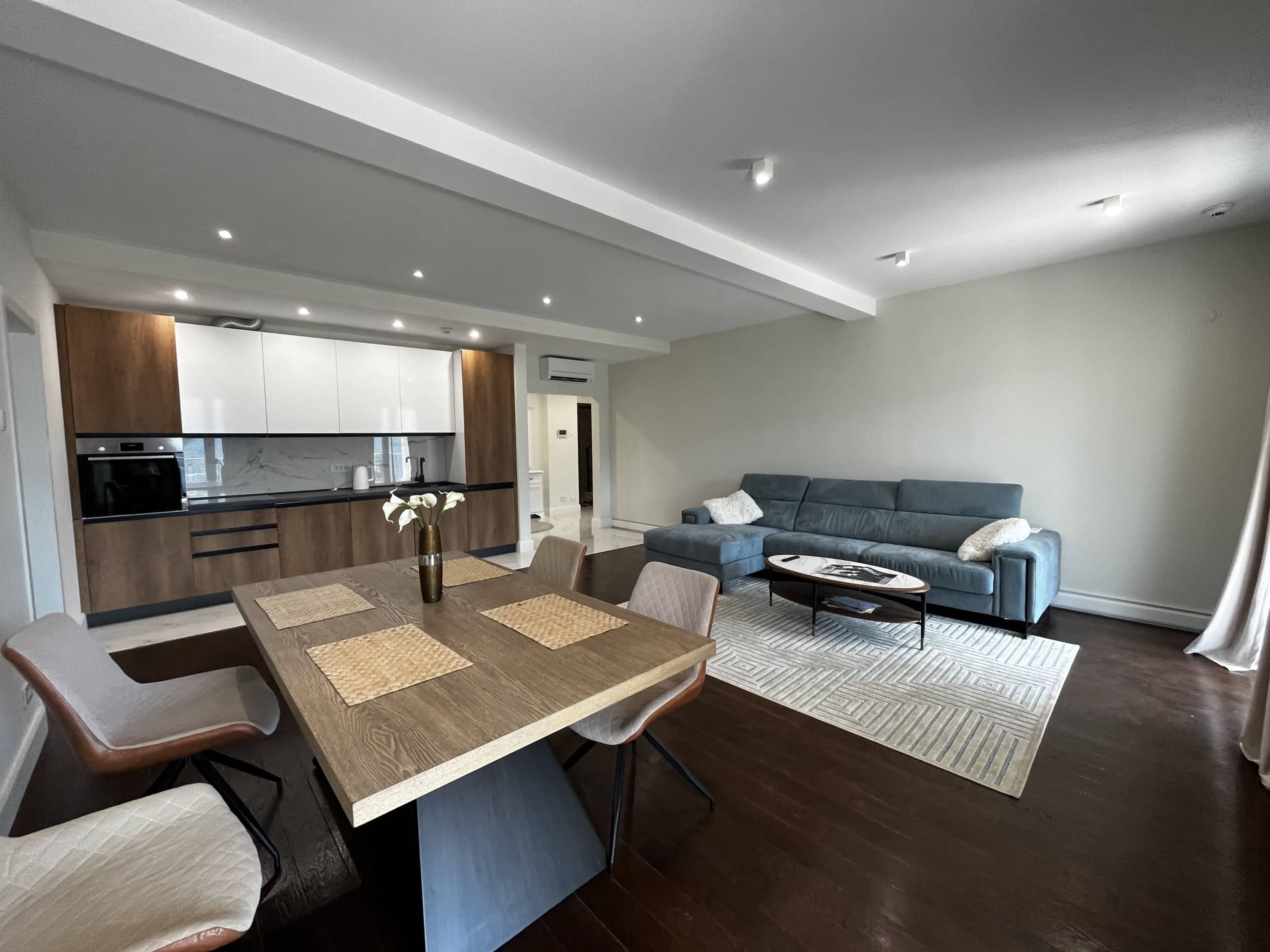 Modern living room with kitchen in the Kumbor residential complex, Montenegro: blue sofa, dining table, and stylish apartment interior.