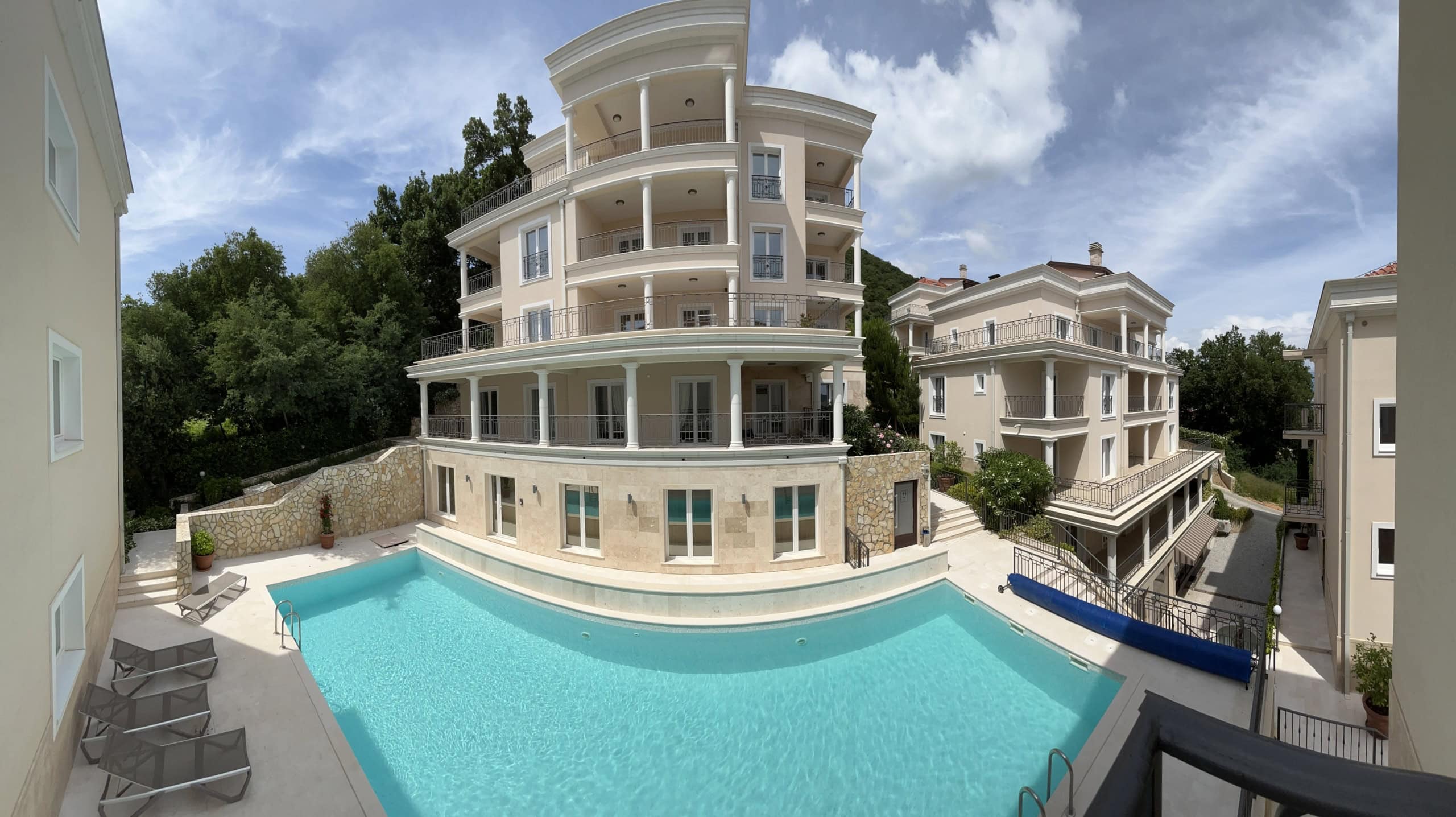 Residential complex in Kumbor, Montenegro: a modern building with terraces, columns, and an outdoor pool in the courtyard.