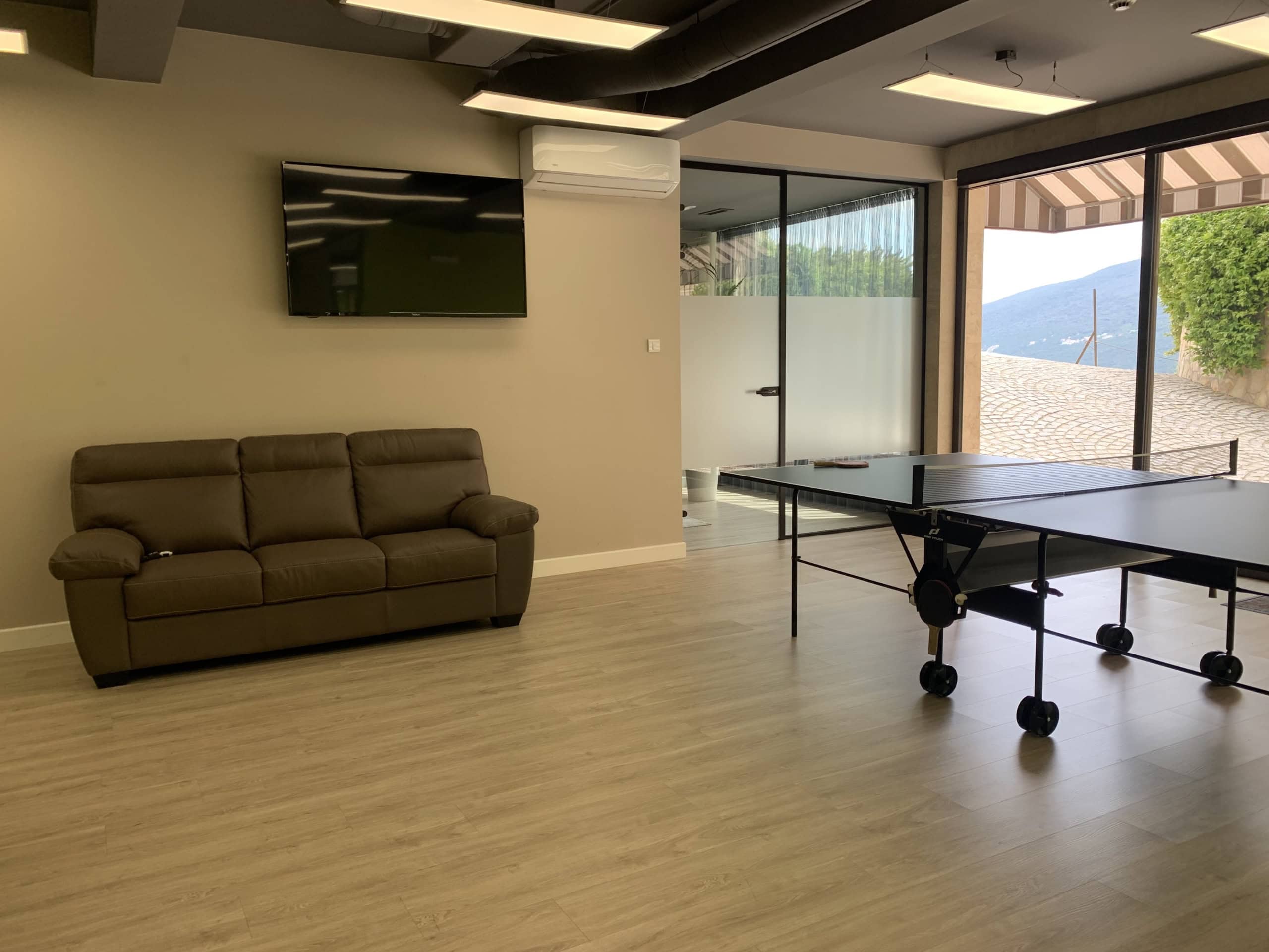 Game room with a ping-pong table and sofa in the Kumbor residential complex, Montenegro: modern interior with panoramic views.