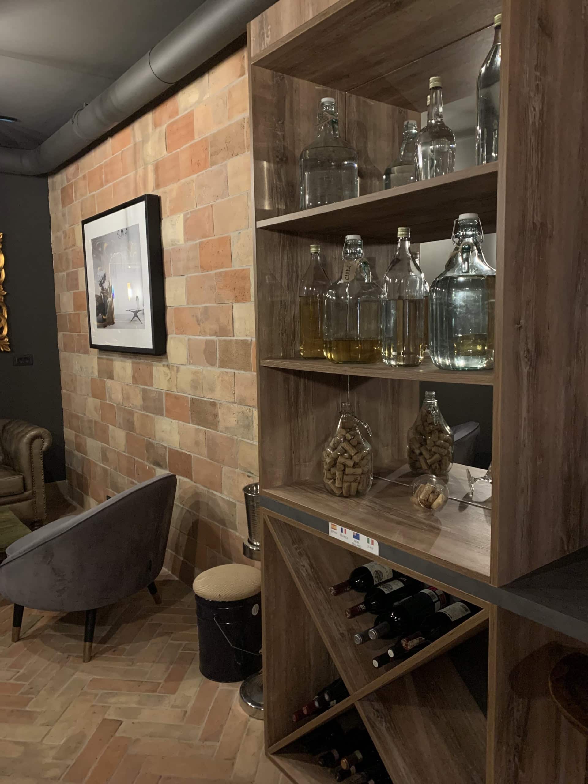 Living room interior in Kumbor, Montenegro: brick wall, wooden wine rack, and a soft loft-style armchair.