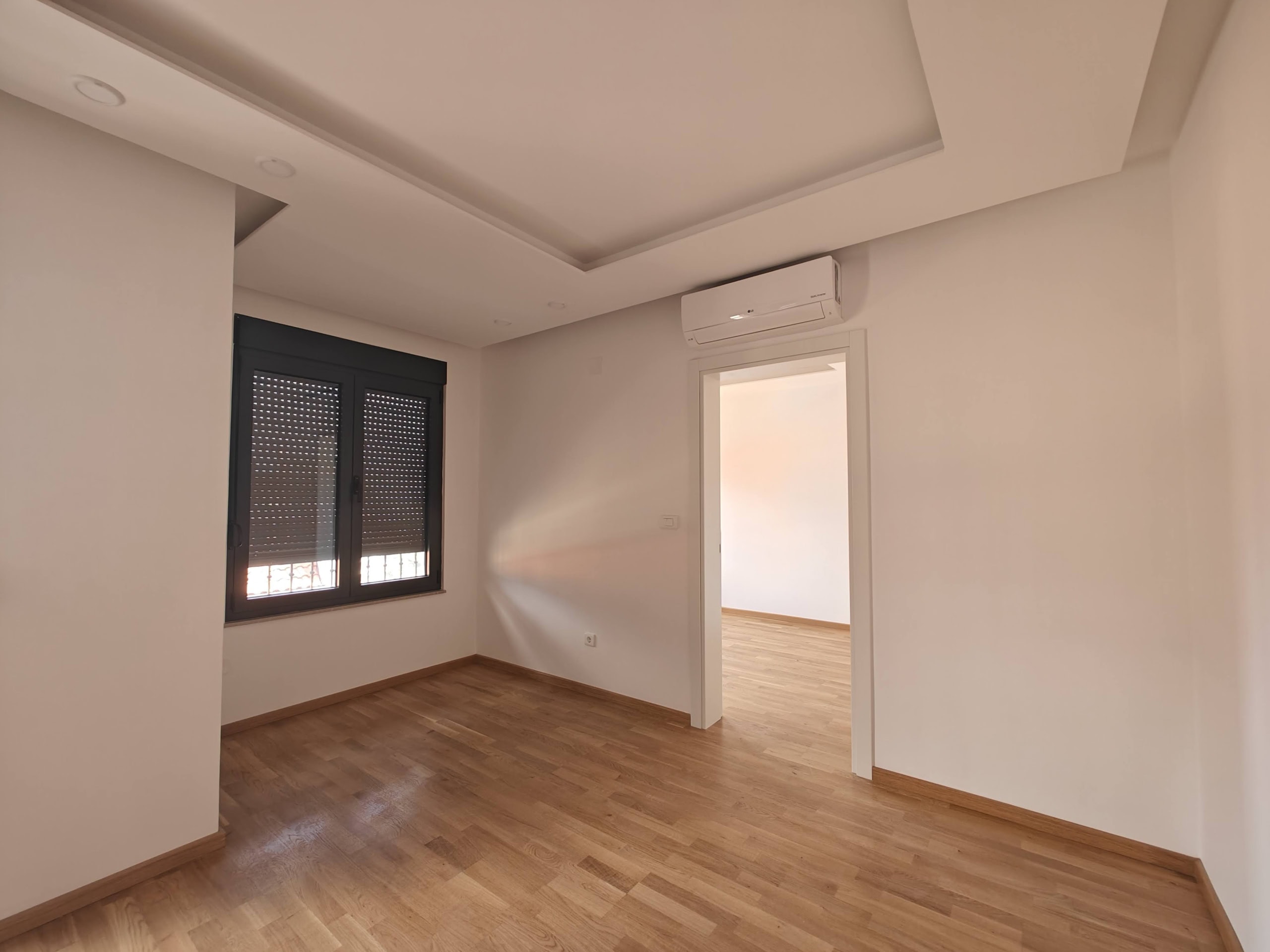 Bright living room with parquet flooring and air conditioning in an apartment for sale in Budva, Montenegro. Modern interior.