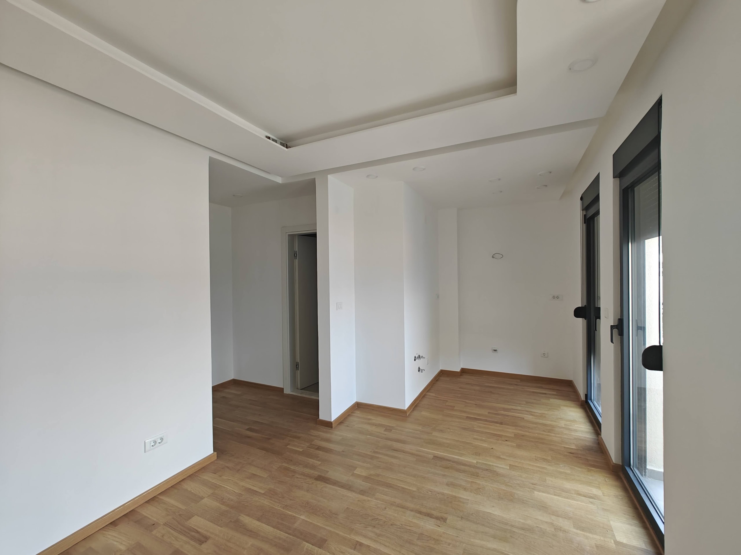 Bright living room with parquet flooring and panoramic windows in a new apartment in Budva, Montenegro. Modern interior.