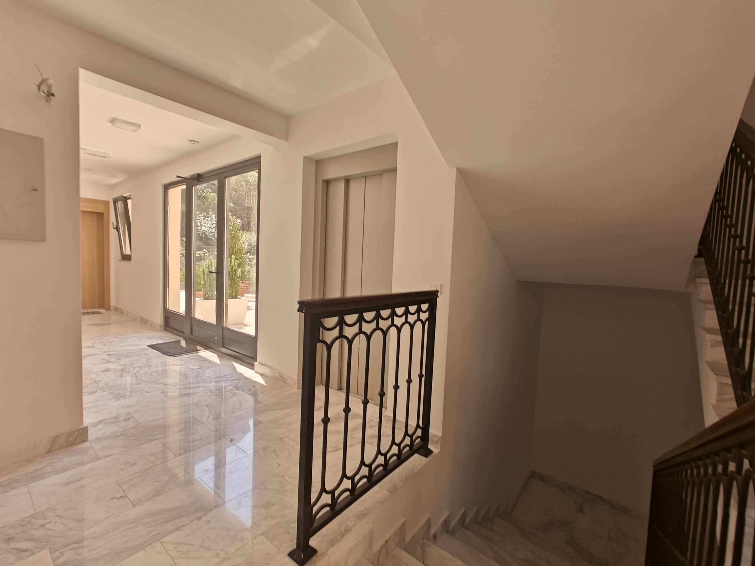 Bright lobby with marble floor, elevator, and staircase in a residential complex in Budva, Montenegro.