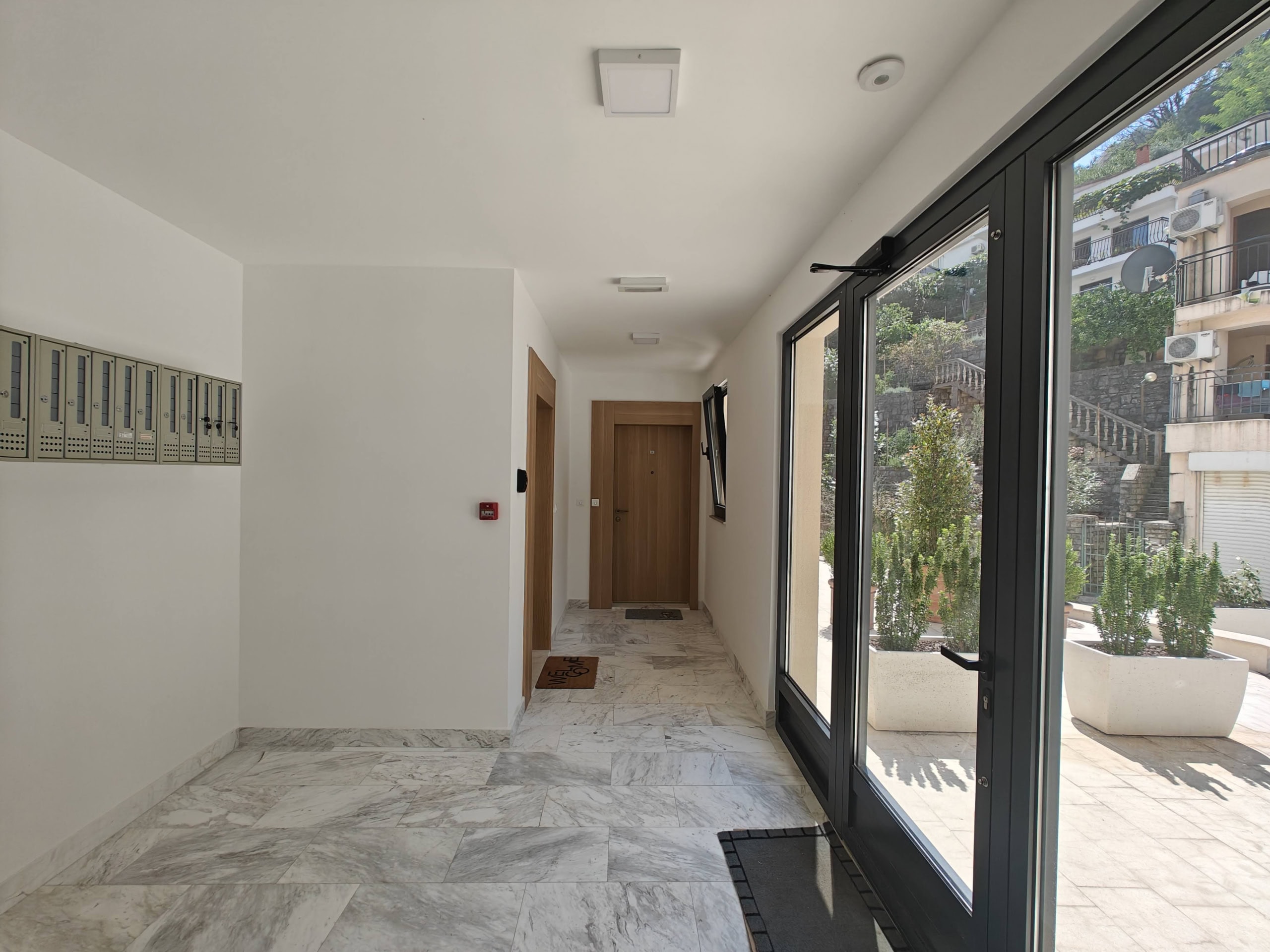 Bright entrance hall with marble floor and mailboxes in a residential complex in Budva, Montenegro, with access to a terrace.