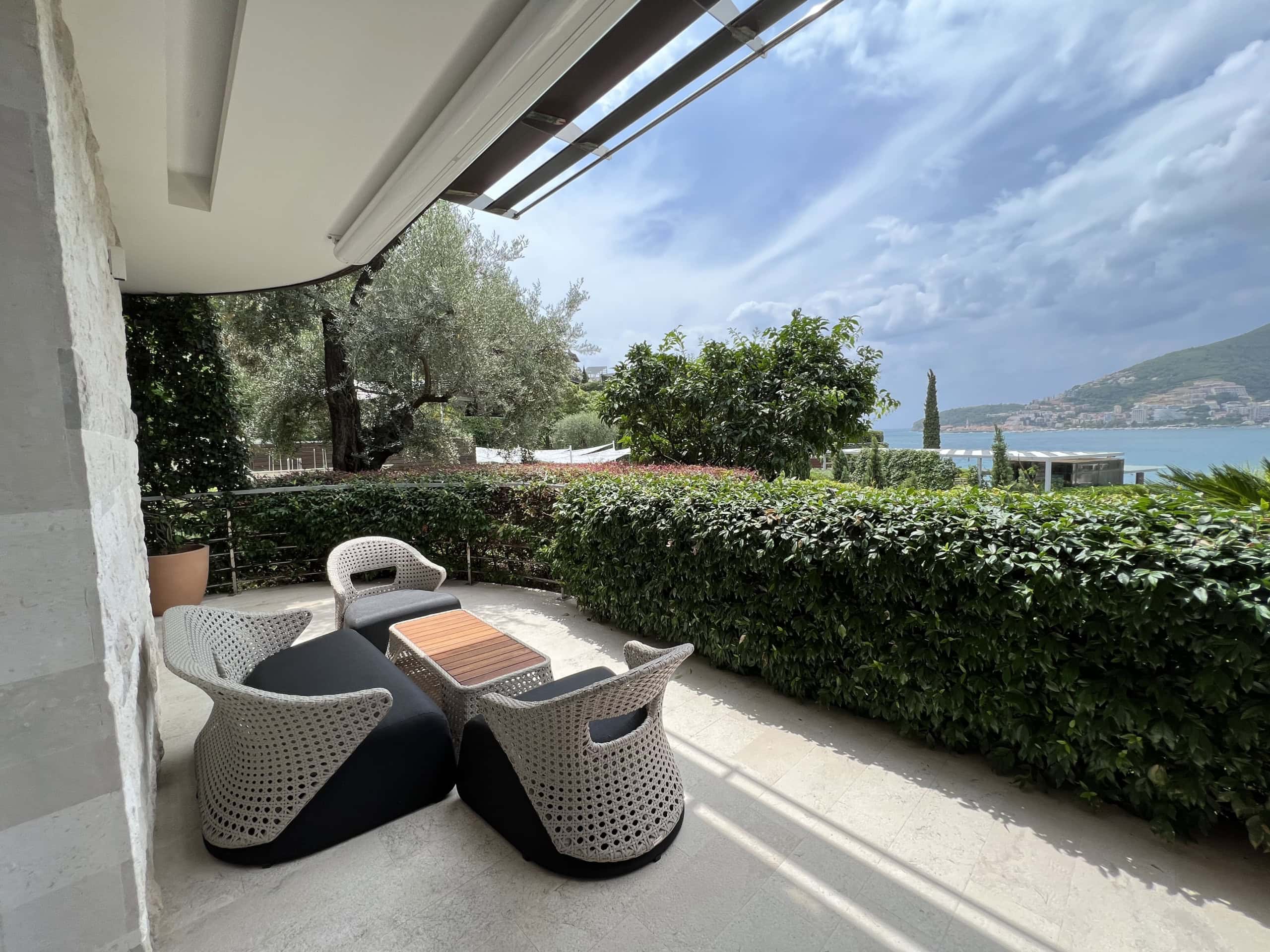 Terrace with wicker furniture and sea view in a residential complex in Budva, Montenegro. Cozy lounge area on the balcony.