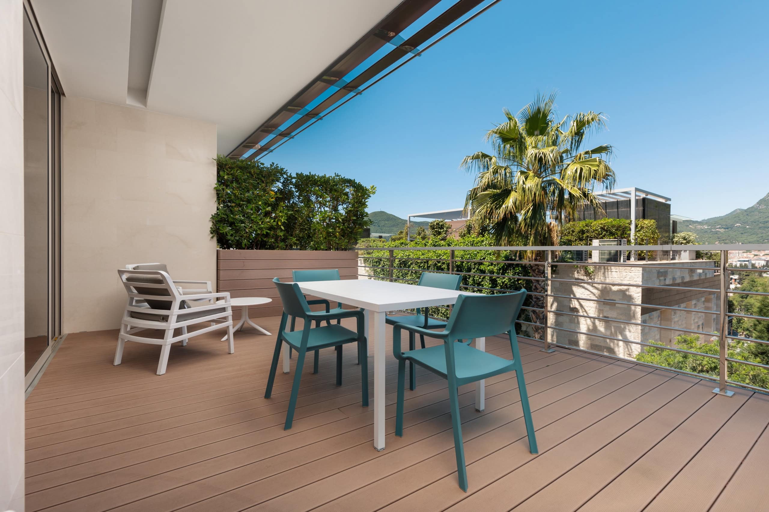 Terrace with furniture in a residential complex in Budva, Montenegro: wooden decking, dining area, and mountain view.