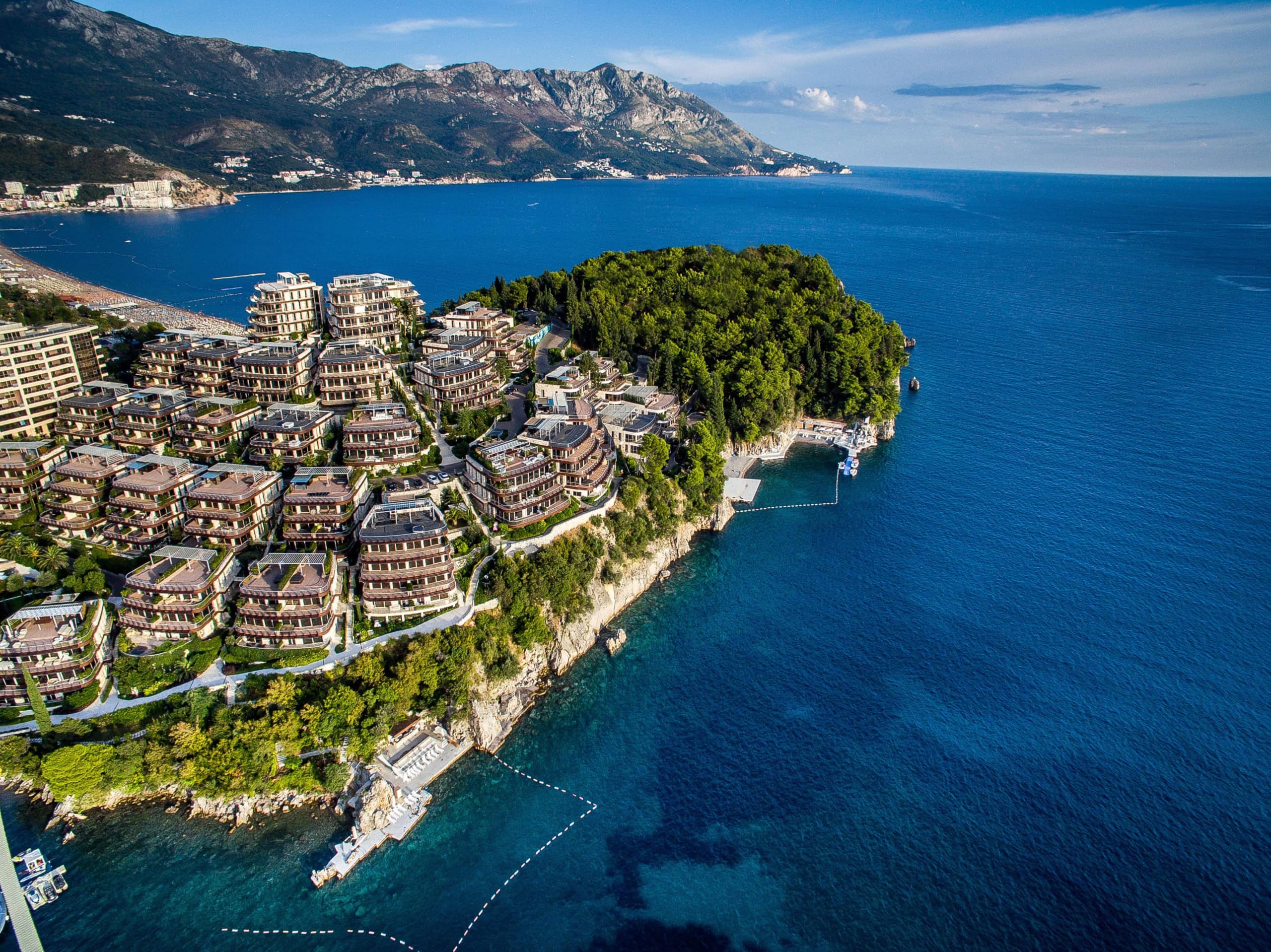 Aerial view of the Dukley Gardens luxury residential complex in Budva, Montenegro, with sea access and mountain views.