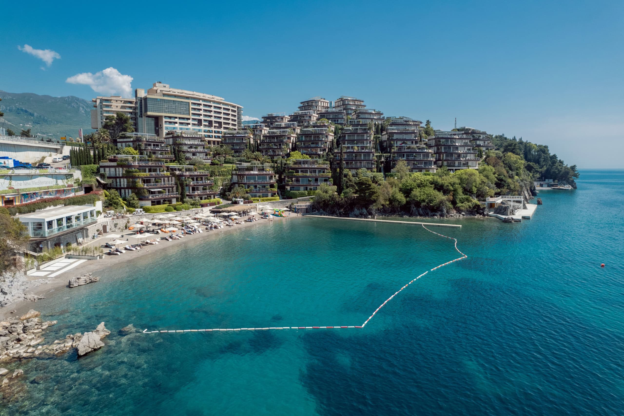 Aerial view of the luxury Dukley Gardens residential complex in Budva, Montenegro, with its own beach and azure sea.