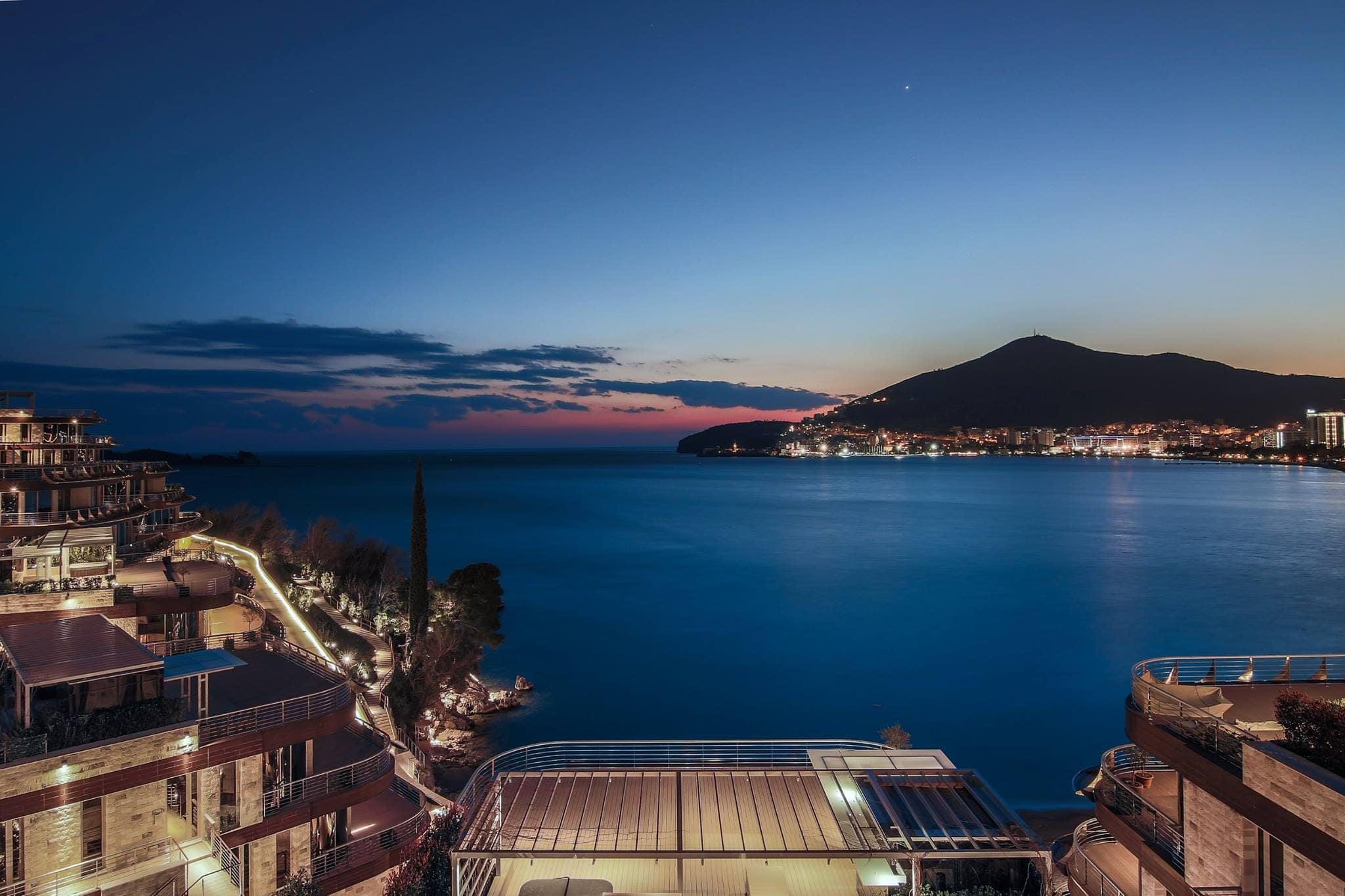 Panoramic view of the sea and night Budva from a luxury residential complex in Montenegro with terraces and illuminated buildings.