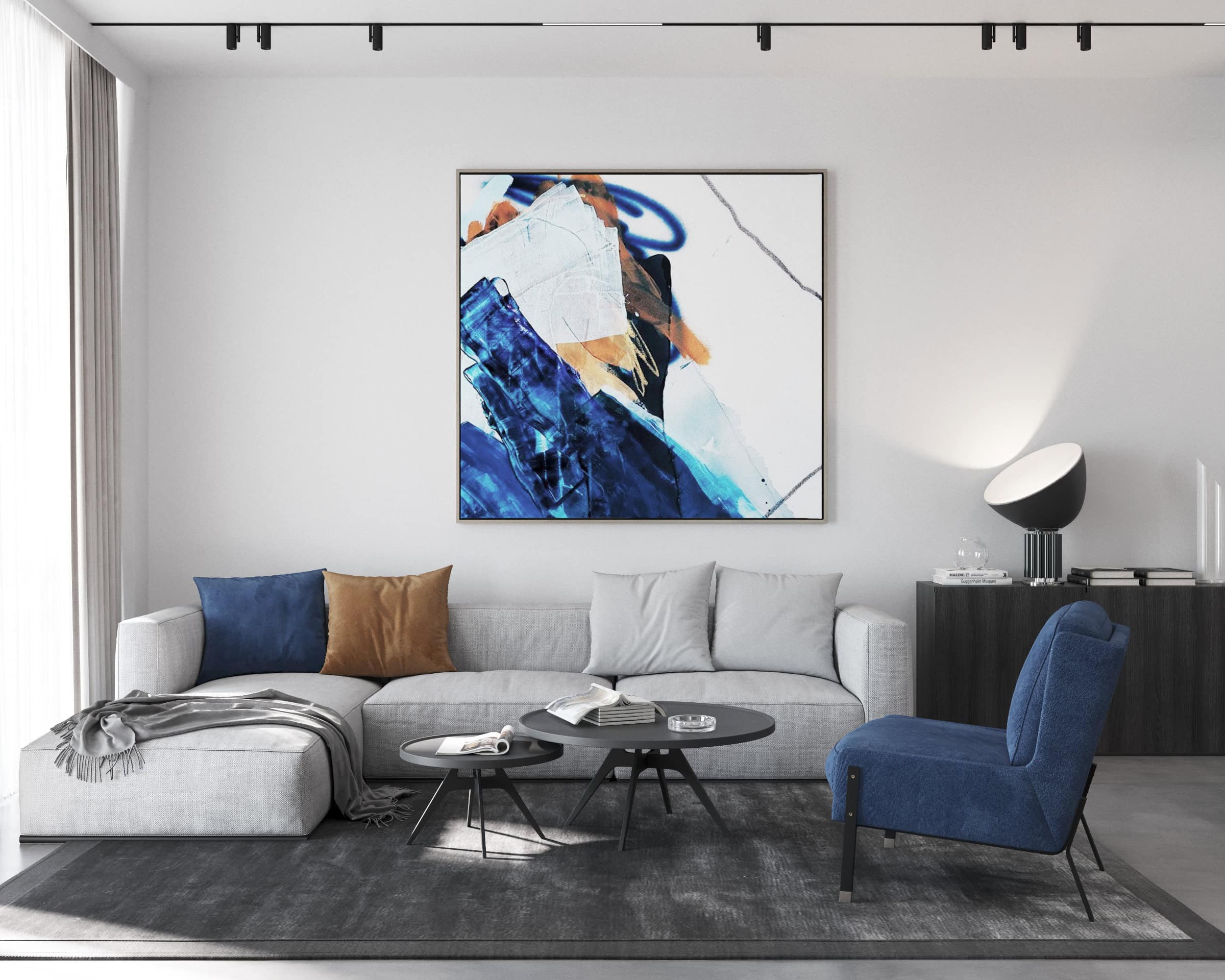 Modern living room in the Tivat residential complex, Montenegro: gray corner sofa, blue armchair, coffee tables, and an abstract painting.