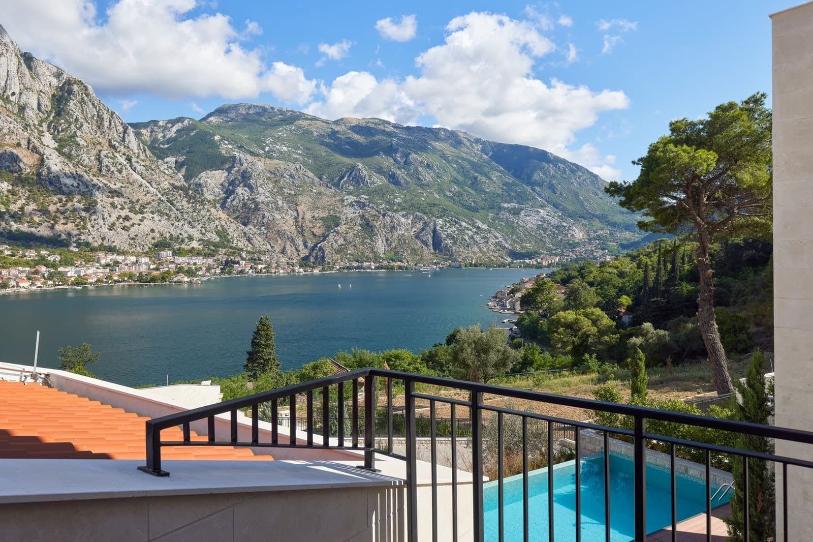 View from the villa balcony in Prčanj, Montenegro: panoramic view of the Bay of Kotor, mountains, and a private pool on the terrace.