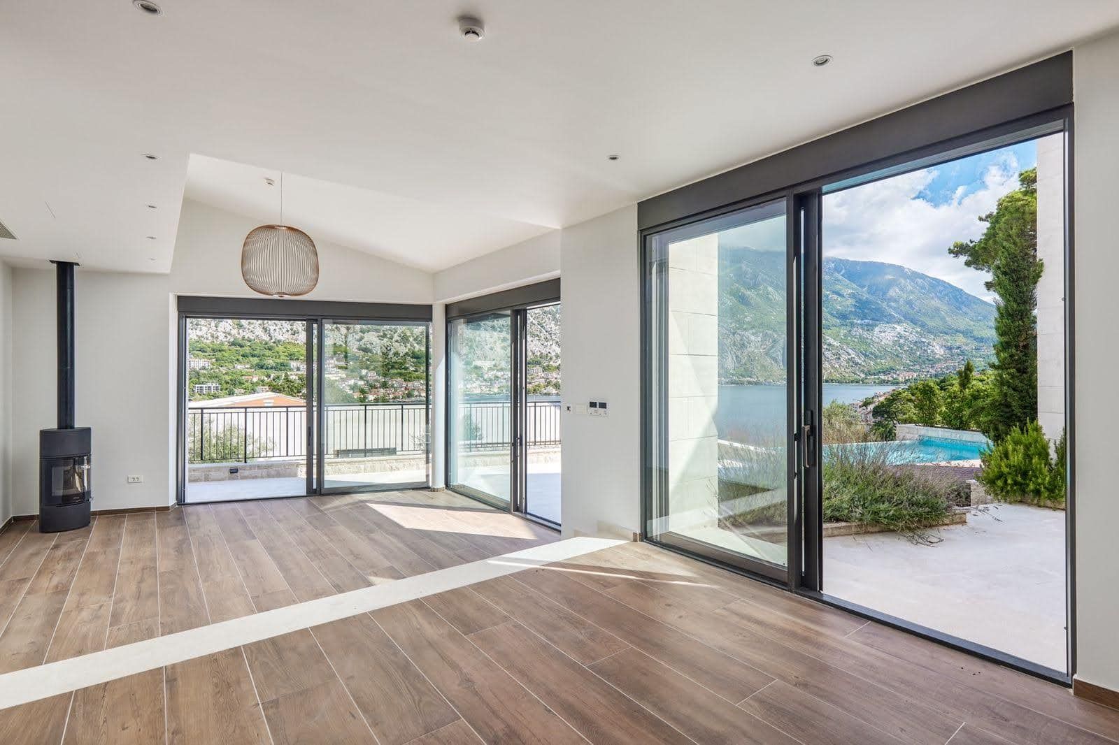 Living room with panoramic windows, a fireplace, and sea and mountain views in a villa, Prčanj, Montenegro. Modern interior.