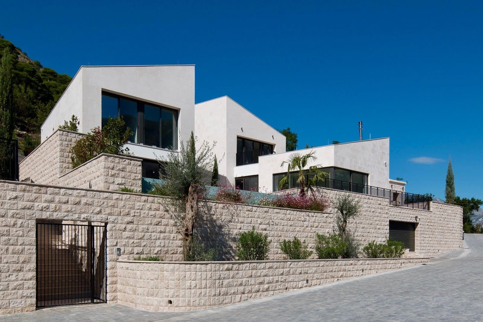 Modern villa in Prčanj, Montenegro: natural stone facade, panoramic windows, and a terrace with a pool.