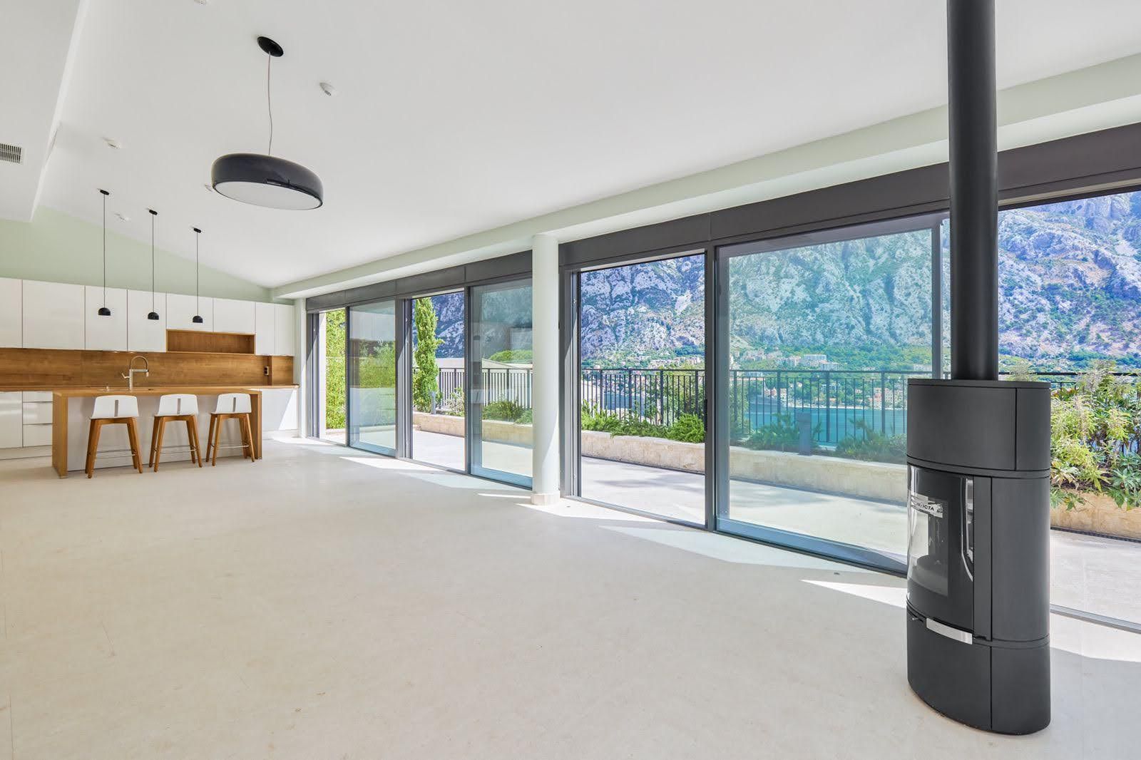 Living room with panoramic windows, a fireplace, and views of the Bay of Kotor, villa in Prčanj, Montenegro.