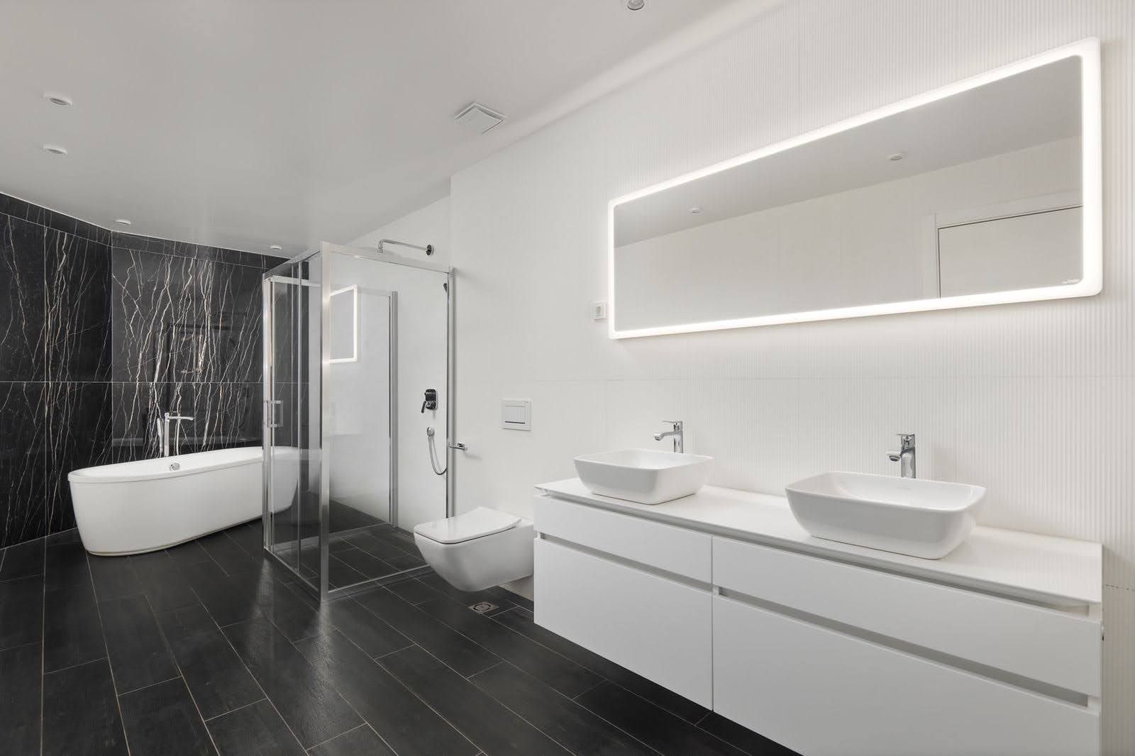 Modern bathroom in a villa in Prčanj, Montenegro: black tile, freestanding bathtub, and double sink.