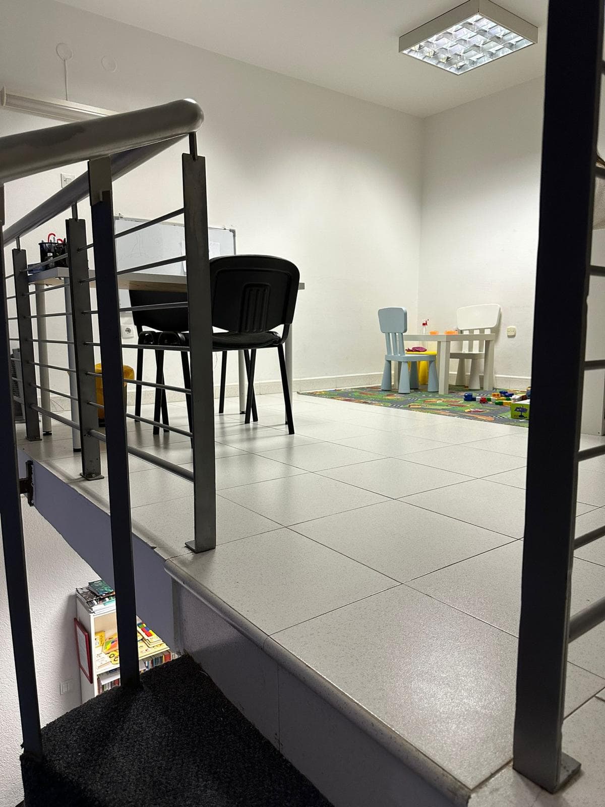 Two-level commercial space in Bar, Montenegro: an area with children's furniture, tile, and a metal staircase.