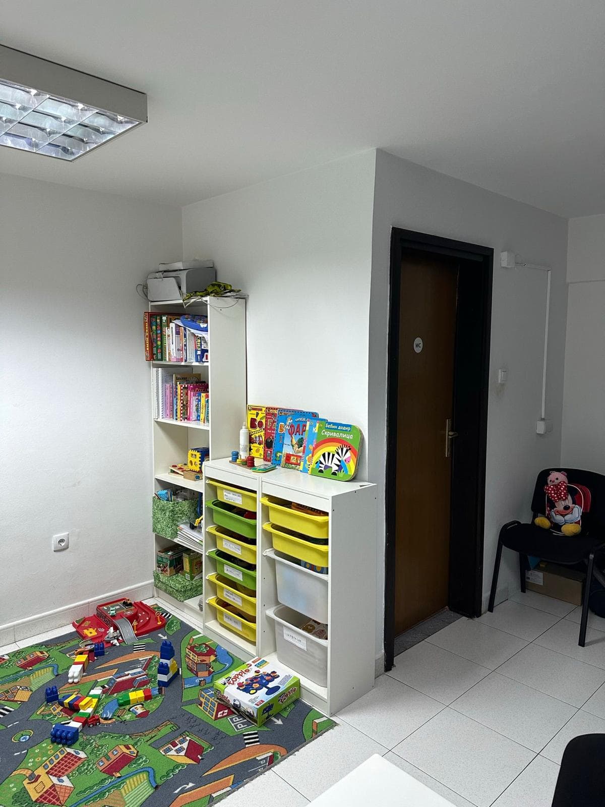 Children’s play area in a commercial space in Bar, Montenegro: shelves with toys and a rug with roads.