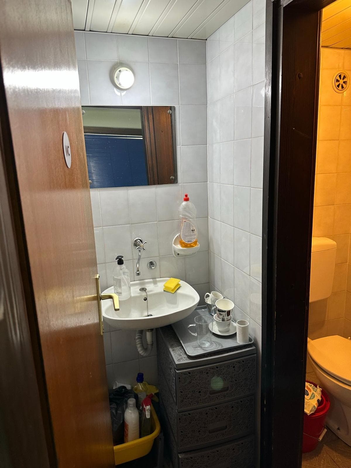 Bathroom in a commercial space in Bar, Montenegro: white tile, sink and toilet, interior view.
