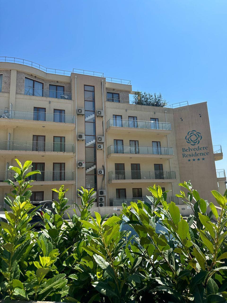 Facade of the Belvedere Residence residential complex in Bečići, Montenegro: a modern building with balconies and glazing.